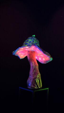Leuchtende Fliegenpilz Skulptur mit LED Beleuchtung unter dem Hut. Der Pilz ist gelb mit blauen Flecken.