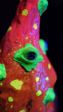 Leuchtende Pilz Skulptur mit spitzem Hut und Augen im UV-Licht